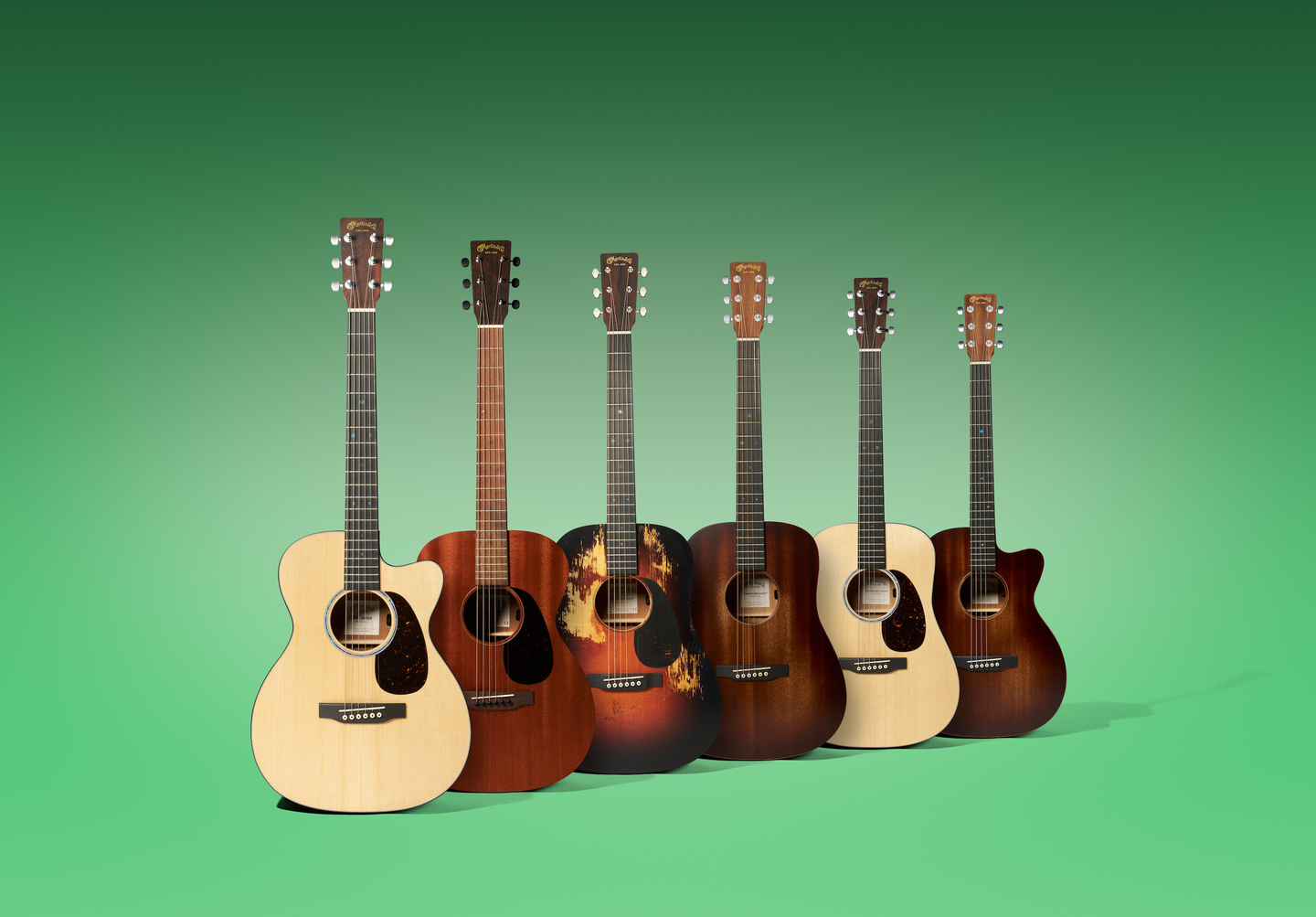 6 Junior Martin guitars on a green background